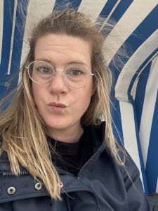 Bild von Karen, wie sie im Strandkorb sitzt bei Regenwetter und Wind an der Nordsee.