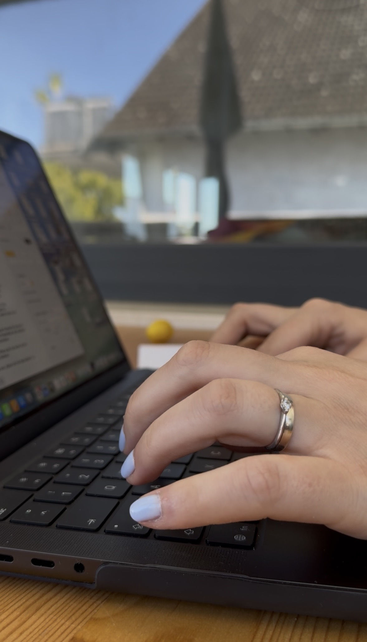 Hände von Karen Blömer wie sie auf der Tastatur des Laptops einen Blogartikel schreiben mit blau lackierten Nägeln.