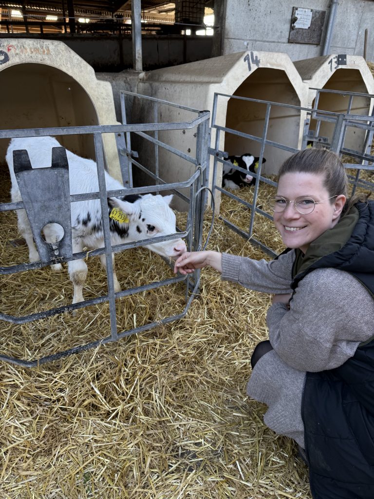 Karen in der Hocke vor einem kleinen Kälbchen.